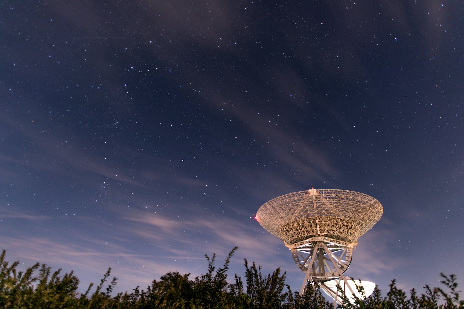 A radio telescope dish under a starry sky